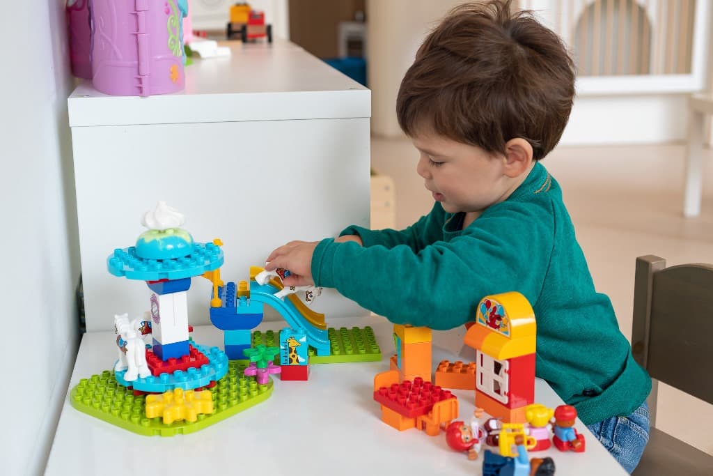 Een peuter speelt geconcentreerd met Duplo