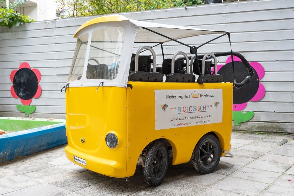 De tuin met de zandbak en de gele bolderbus van Kinderdagpaleis Boerhaave
